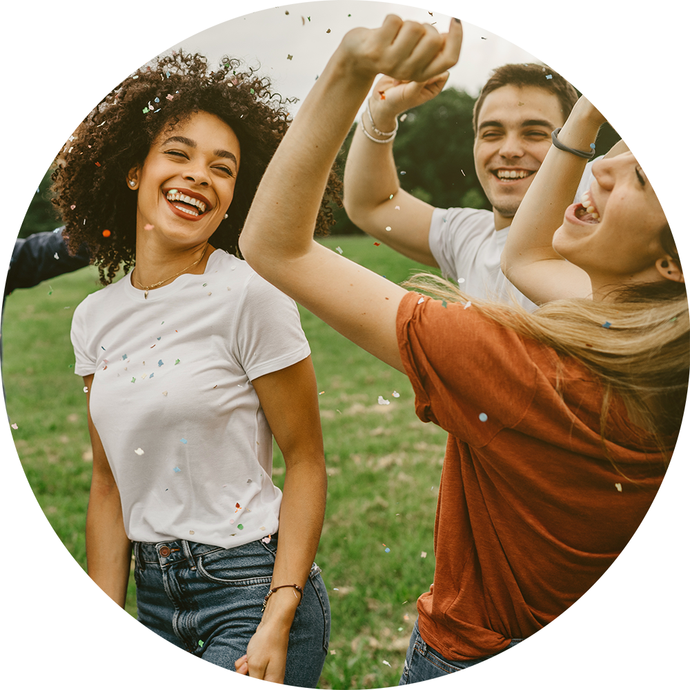 This image depicts a group of young adults celebrating outdoors, possibly at a party or event, as evidenced by the confetti falling around them. They appear to be laughing and enjoying themselves.
